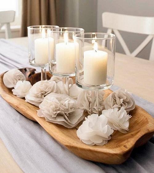 Decoración con velas blancas sobre una bandeja y otros accesorios decorativos.