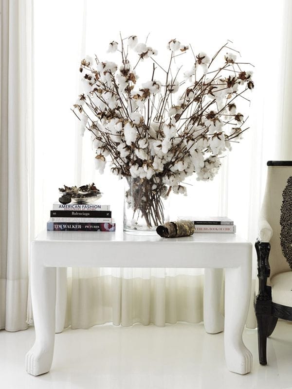 mesa blanca con libros y jarron con algodon