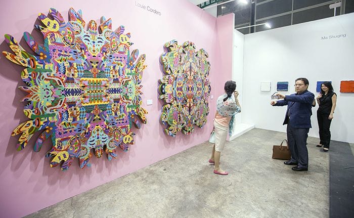 epa04205019 A man takes a photo with his phone of a woman standing in front of an artwork by Filipino artist Louie Cordero entitled 'Thinking Not Seeing, Seeing Not Thinking 1' at Art Basel 2014, Hong Kong, China, 14 May 2014. Art Basel is in its second year in Hong Kong and features 245 galleries from 39 countries. Hong Kong is the third largest art market in the world by auction revenue. The show runs from 15 to 18 May. EPA/ALEX HOFFORD