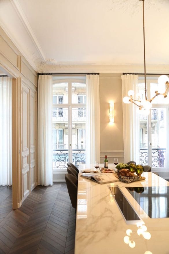 cocina de apartamento con mesa de marmol grandes ventanas aplique pared looshaus