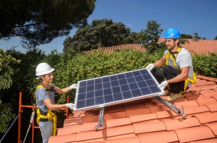 PAreja de profesionales instalando un panel solar en el tejado de una casa
