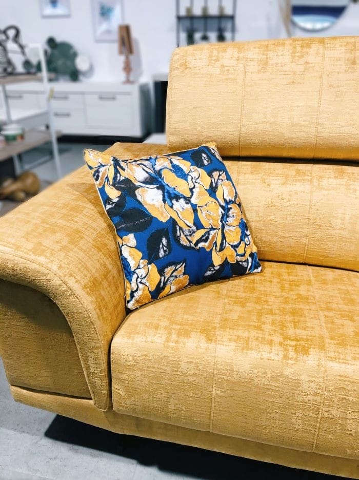 Sofá con un color vivo y encima un cojín estampado colorido