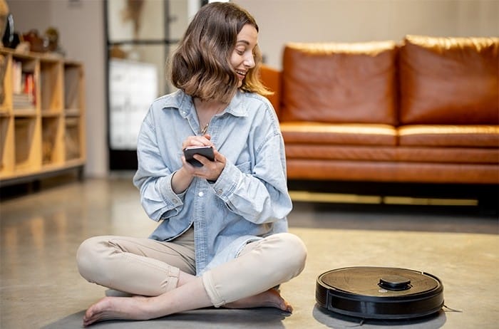 mujer sentada junto a roomba