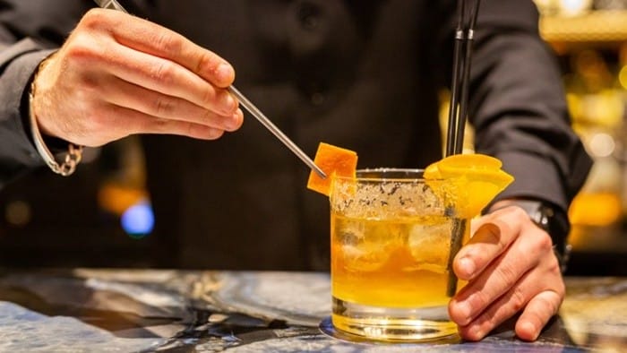 camarero sirviendo copa coctel pajitas