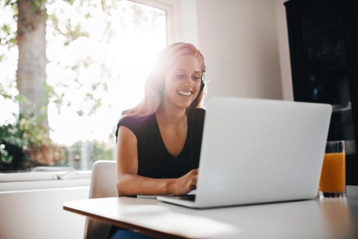 mujer alegre trabajando desde casa con su portátil