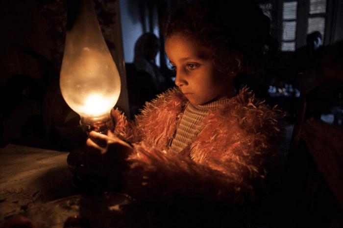 Niña con una lámpara en una zona de conflicto