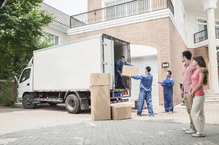 Pareja viendo a los trabajadores de una empresa de mudanzas subiendo cajas al camión