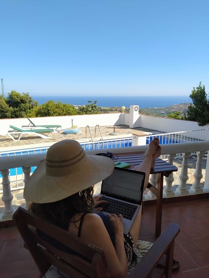 mujer en una terraza con piscina y al fondo el mar