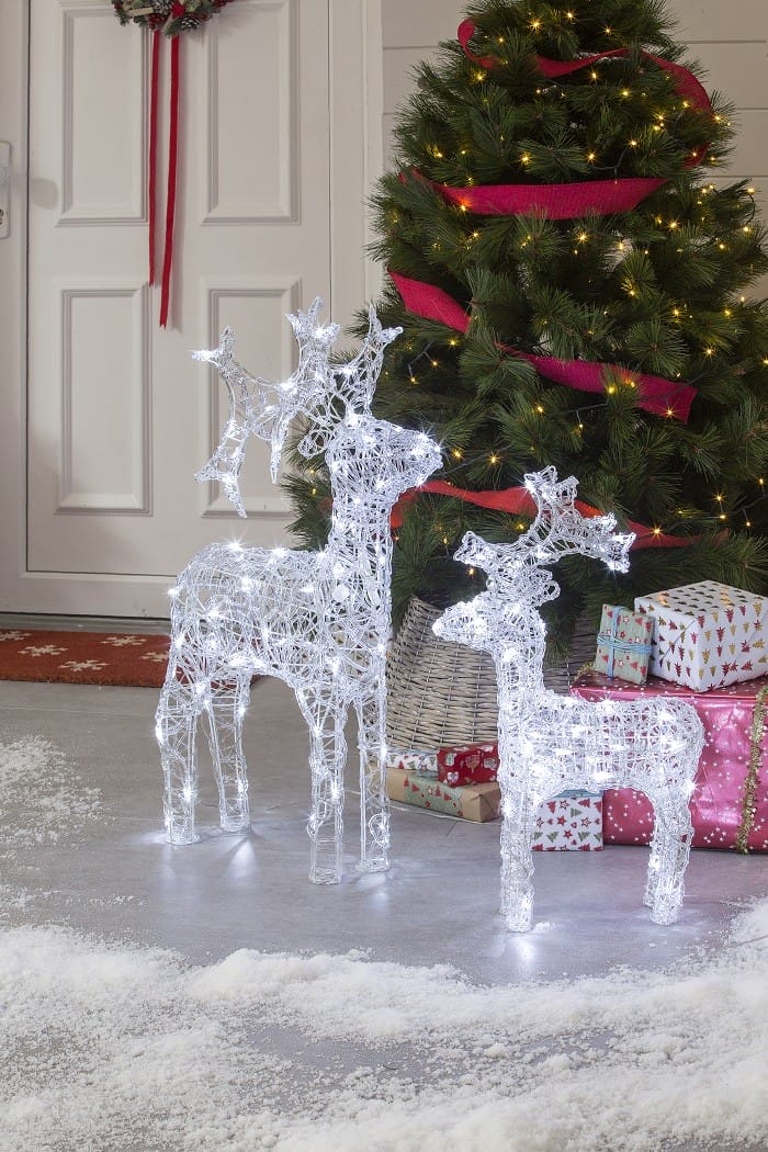 ciervos iluminados con árbol de Navidad en la puerta de una casa