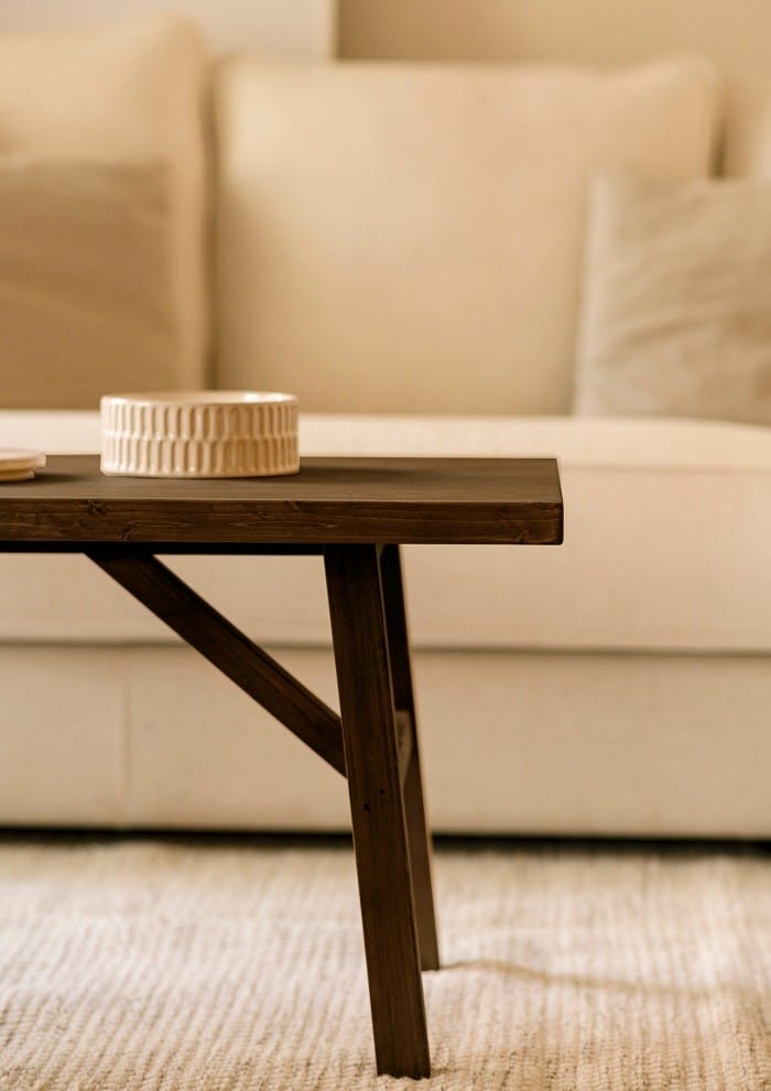 mesa de madera de nogal en salón con sofá blanco de fondo