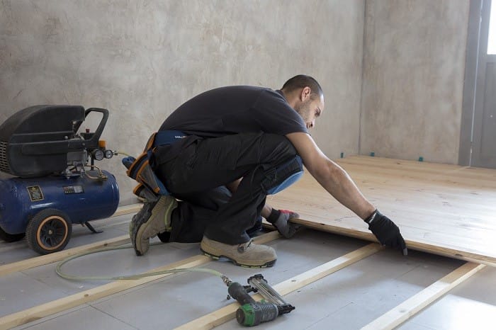 Trabajador instalando un suelo de madera maciza clavada