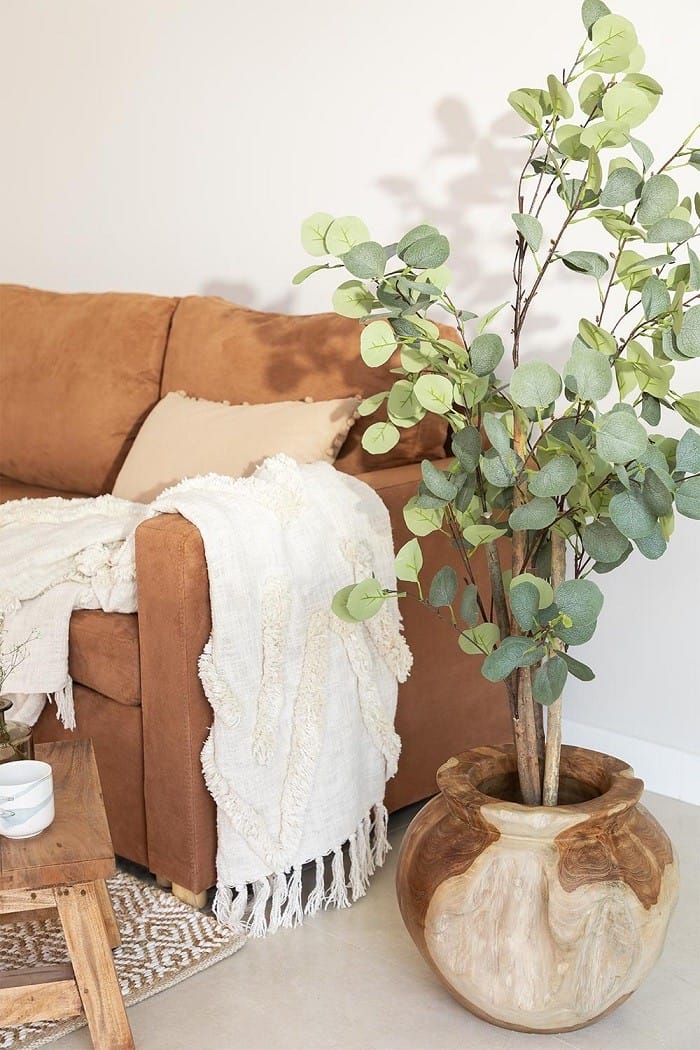 salón con un jarrón en madera con plantas