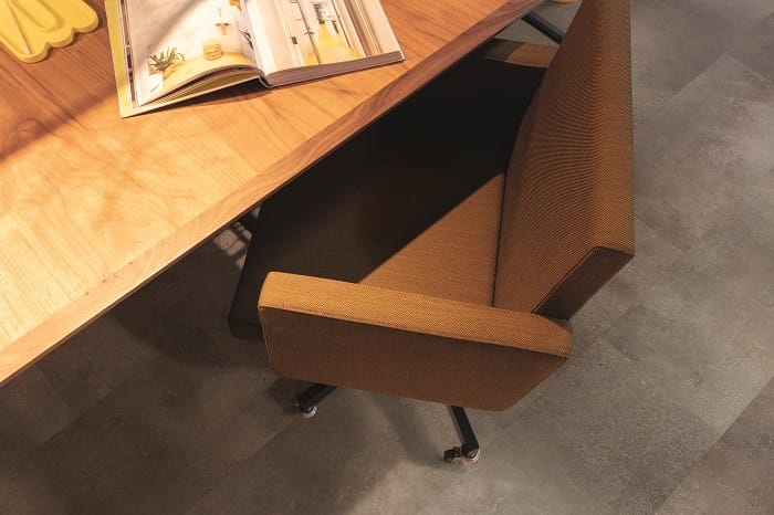 Detalle de una mesa de madera con sillón en suelo estilo industrial