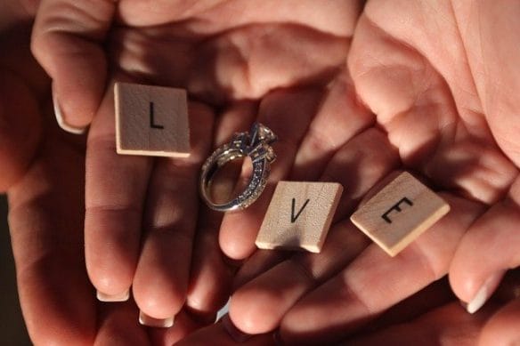 manos abiertas con letras y un anillo de compromiso para regalar en San Valentín