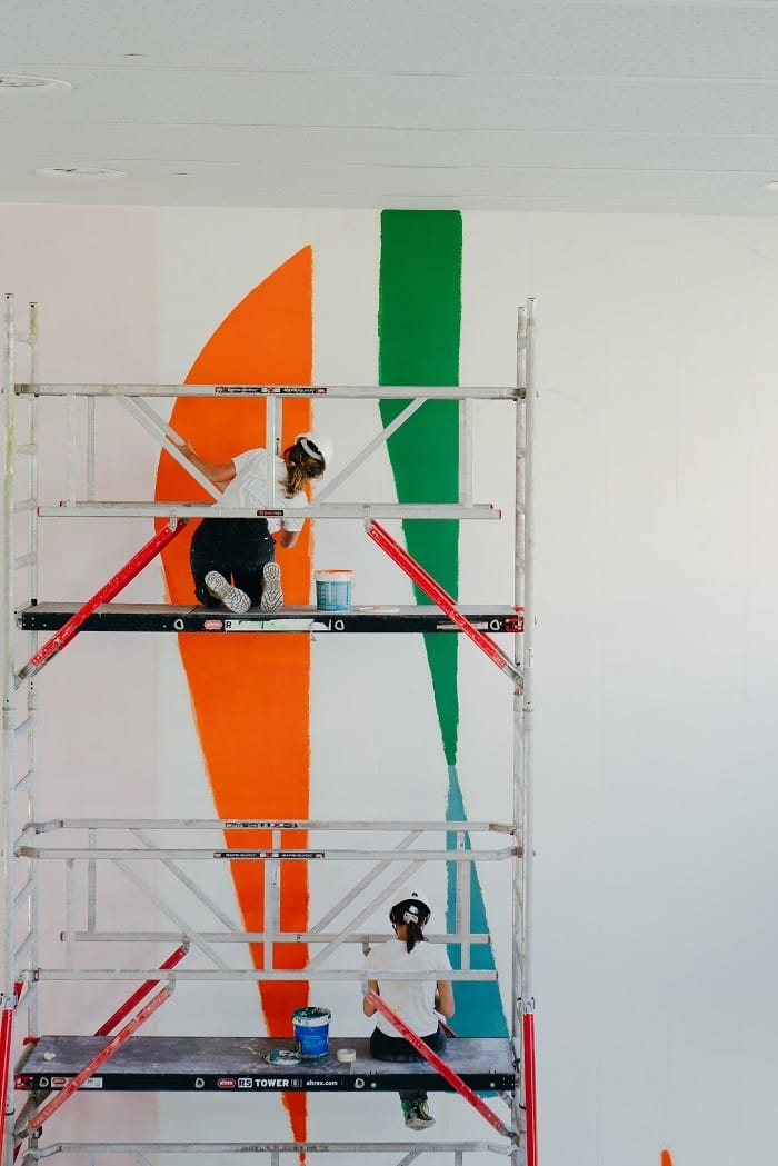 chico pintando un mural subido al andamio