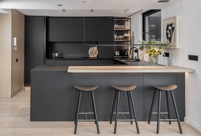 cocina de color negro con taburetes en su isla