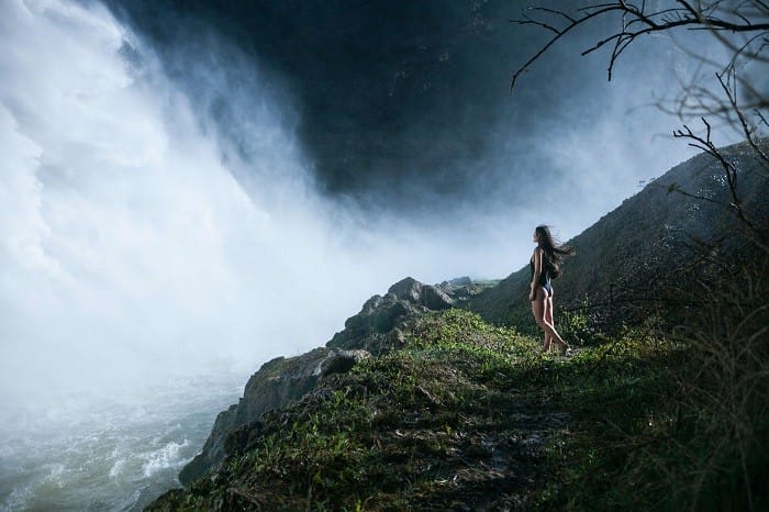 Paisaje verde con cascada de río con mujer en bañador