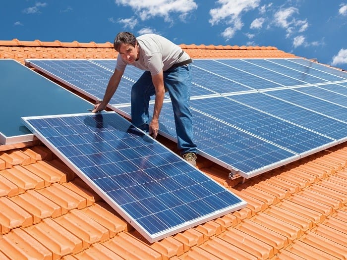 Instalador colocando paneles solares en el tejado de una casa