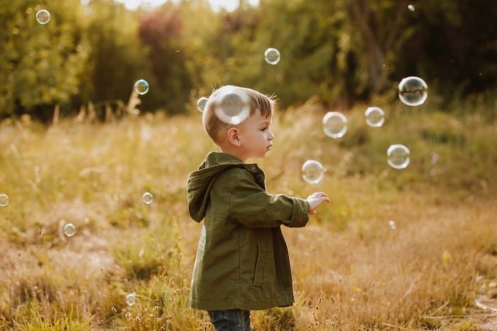 niño con pompas en el campo