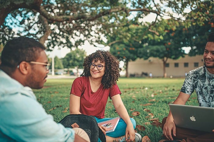 estudiantes sentados en cesped campus