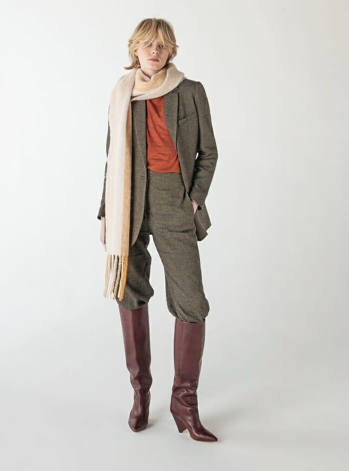 modelo con pantalones y chaqueta verde con bufanda