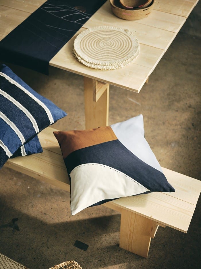 Funda de cojín de varios colores de Ikea encima de un banco de madera