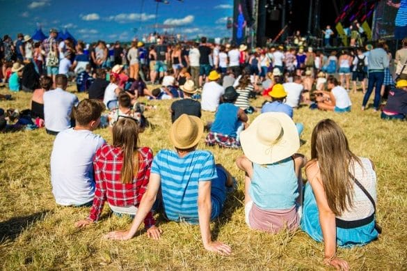 Grupo de personas sentadas en el suelo escuchando un festival de fondo