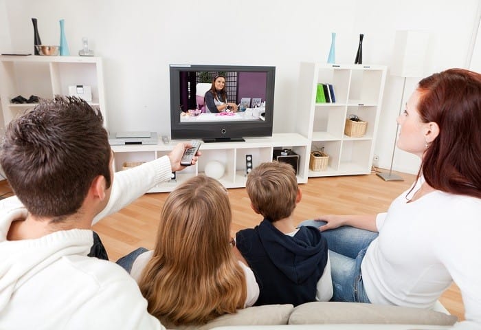 Familia en el sofá de su casa viendo la televisión