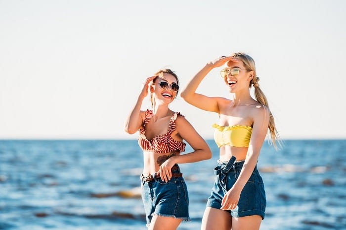 Dos amigas en la playa en bikini y vaquero corto