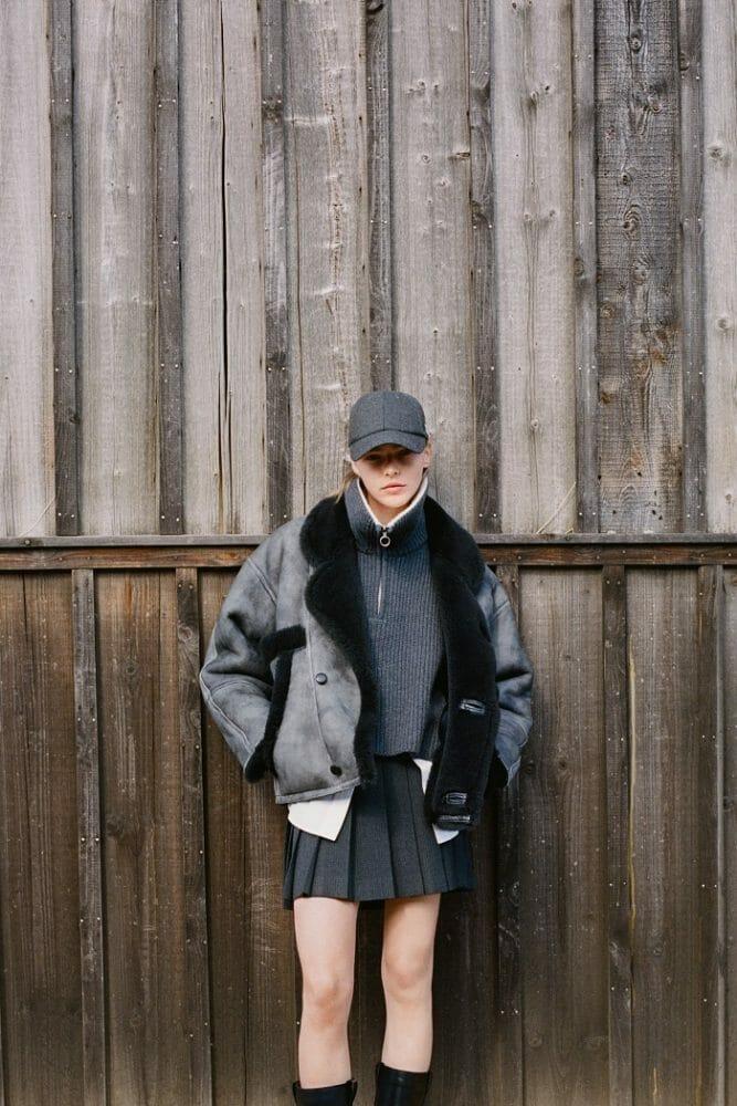 modelo con falda de tablas, jersey y chaqueta