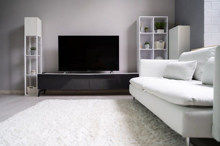 Salón con sofá blanco y televisión sobre mueble de TV
