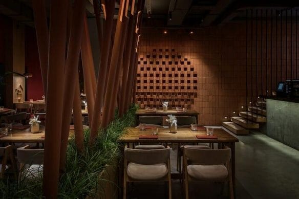 Mesa con plantas en restaurante Tanuki con pared de ladrido salido original