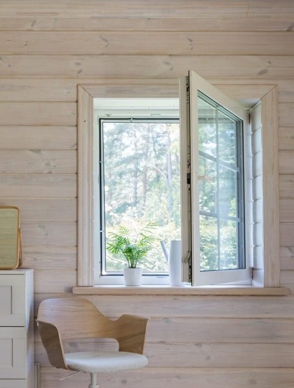 Interior de una casa de madera con ventana con mosquitera enrollable y planta