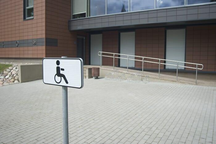 Calle con señal para aparcar minusválidos y un rampa de fondo