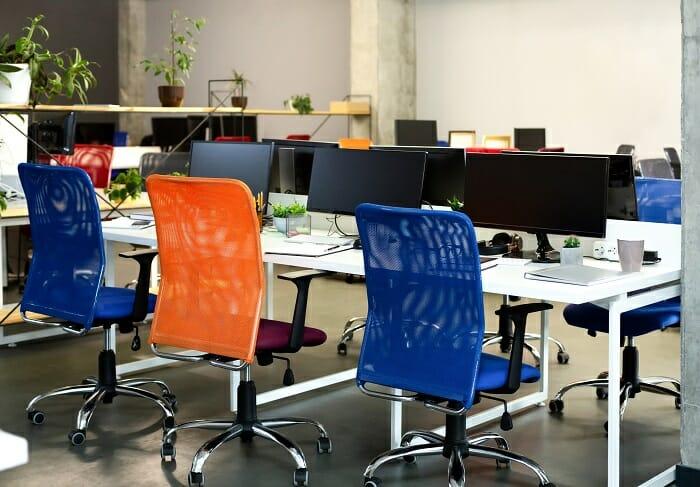 Interior de un espacio de trabajo con mesas y sillas de escritorio ergonómicas de diferentes colores
