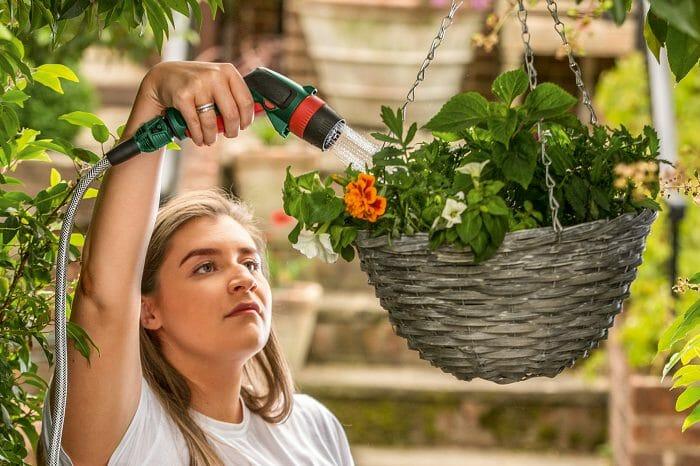 Chica regando sus flores del jardín