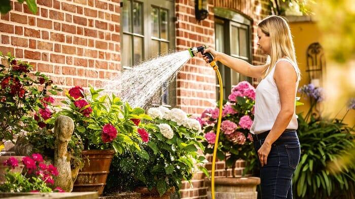 Mujer en su jardín regando sus flores con la bomba Bosch 18V