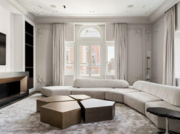 Salón con gran sofá blanco y mesita de madera con un diseño clásico de interiorismo