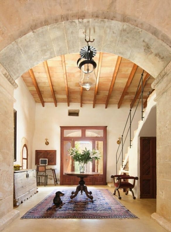 Salón con arco de medio punto en la pared y vigas de madera en el techo de casa rural