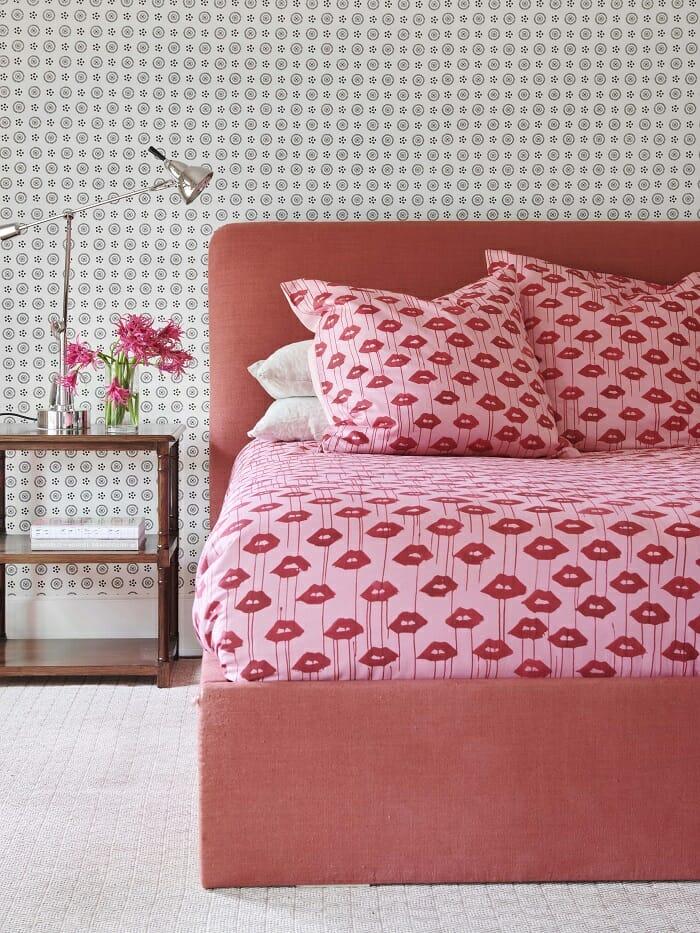 Cama con ropa de cama de estilo Barbiecore en tonos rosas y besos rojos