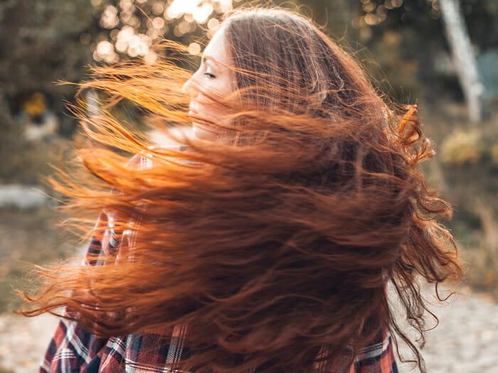 mujer joven pelo largo pelirrojo al viento