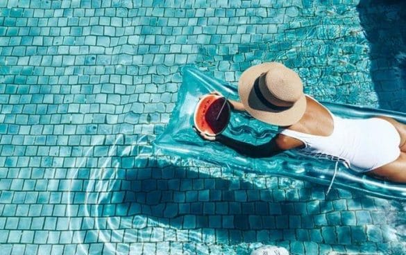 Mujer con sombrero sobre una colchoneta en una piscina