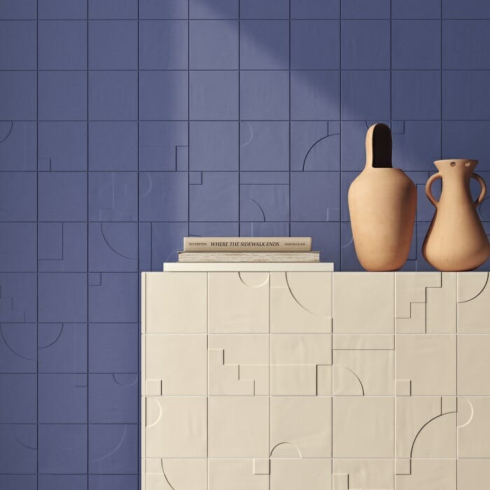 Pared en azul con relieve con piezas de cerámica y otra en color beige con jarrones y libros
