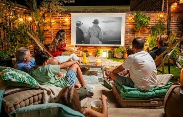 Familia viendo un cine de verano en su terraza