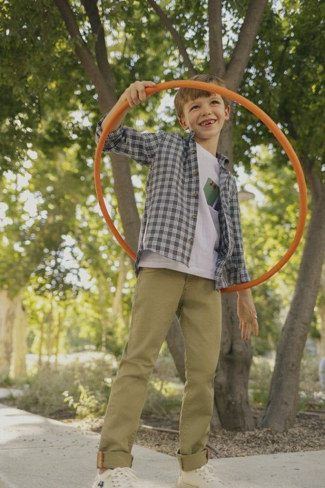 Niño en la calle jugando con un aro y con ropa Scotta