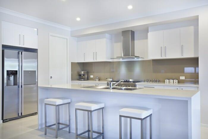 Interior de una cocina abierta con isla con taburetes y un frigorífico moderno doble