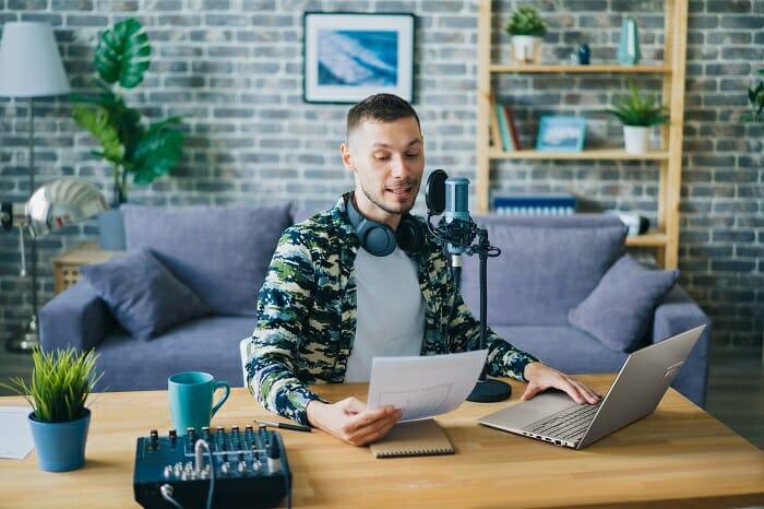 Chico en su escritorio con un portátil ASUS leyendo una hoja con micro y cascos
