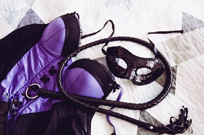 Corsé morado erótico con antifaz y látigo