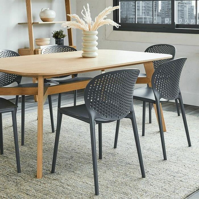 Espacio de hogar con mesa de madera y sillas de plástico negras