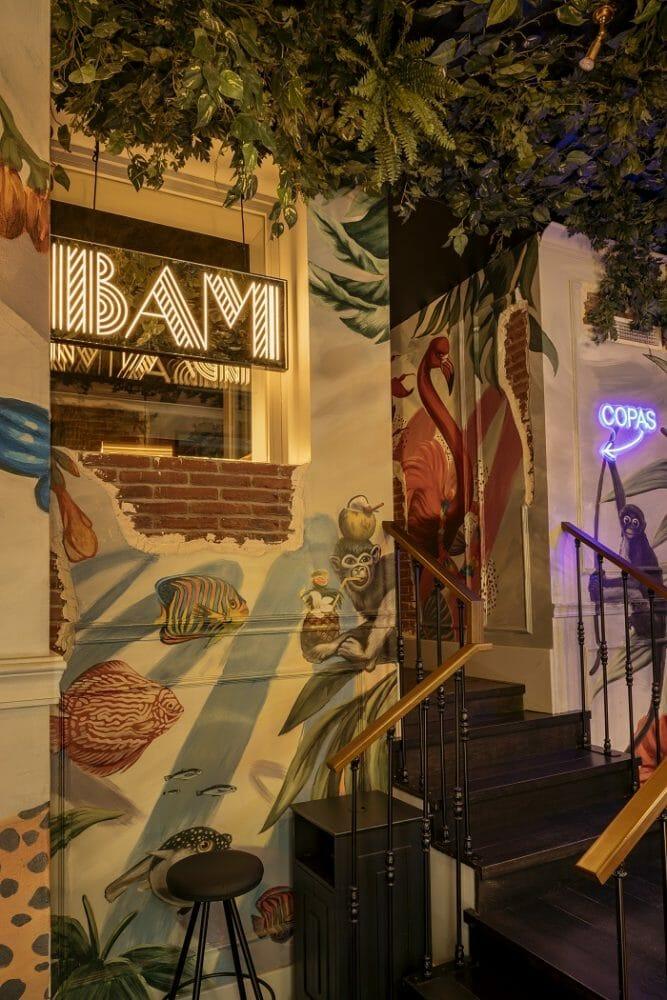 Escaleras del restaurante Bam Karaoke Box con una decoración en la pared animal y plantas